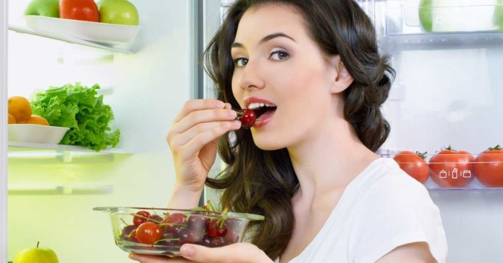 Top Benefits of glass food storage containers. Woman eating cherries from glass bowl